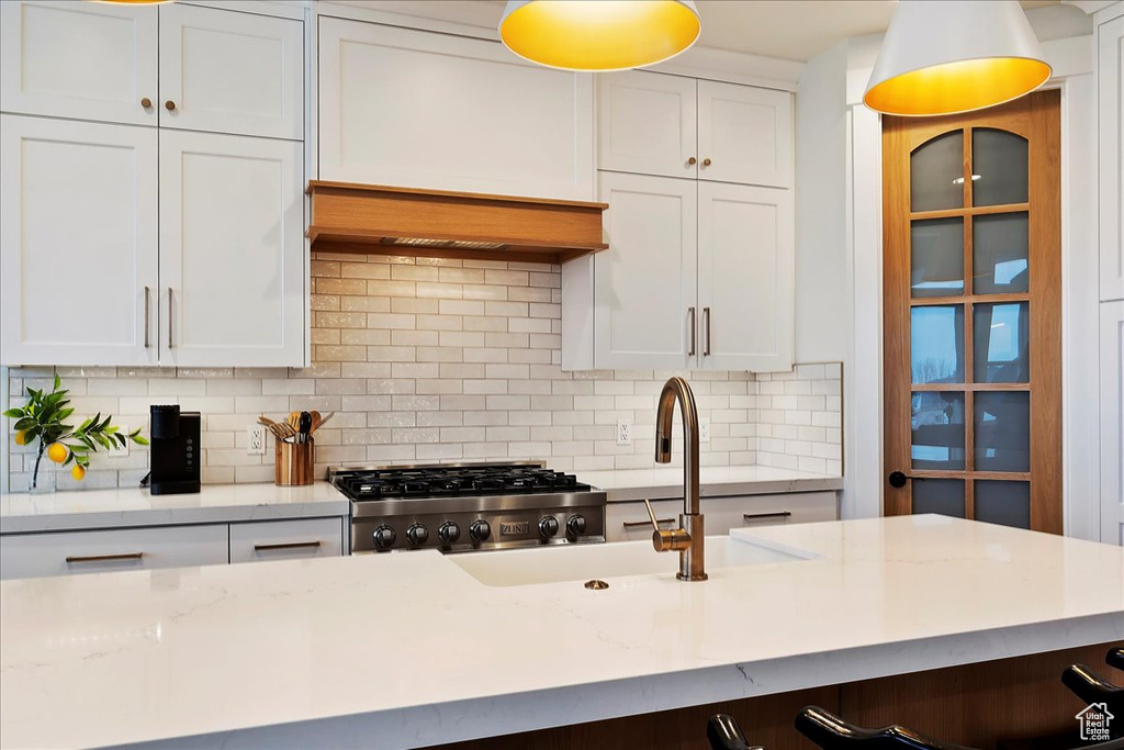 Kitchen featuring white cabinets, backsplash, and light stone counters