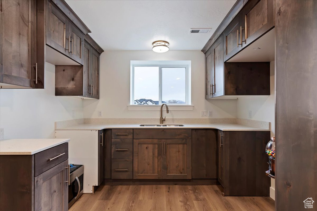 Kitchen featuring dark brown cabinetry, sink, and light wood-type flooring