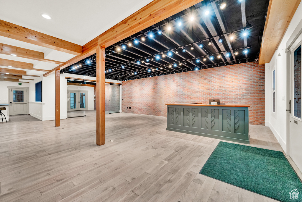 Basement with brick wall and light hardwood / wood-style flooring