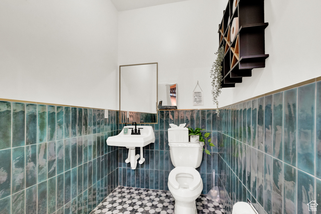 Bathroom with tile flooring, tile walls, sink, tasteful backsplash, and toilet