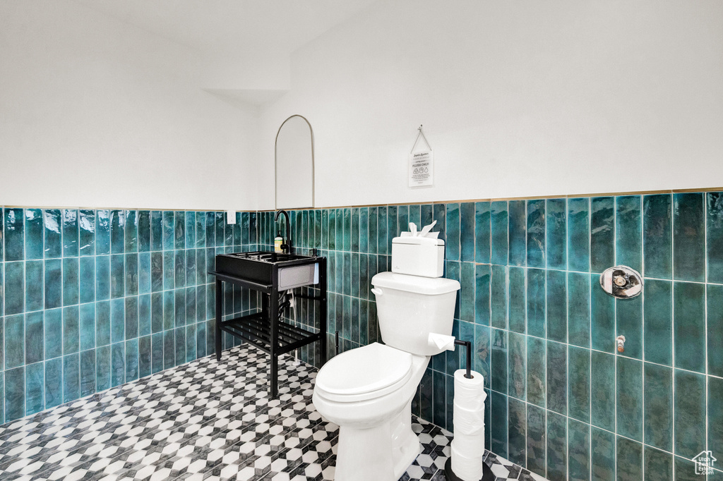 Bathroom featuring tile walls, toilet, and tile floors