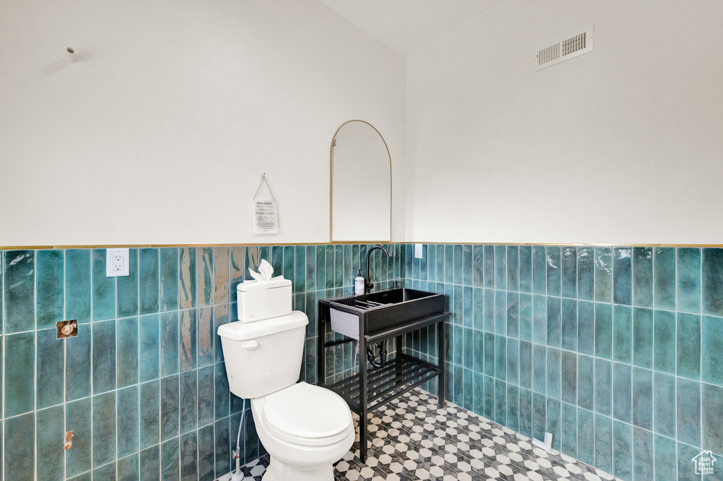 Bathroom with tile walls, toilet, and tile flooring