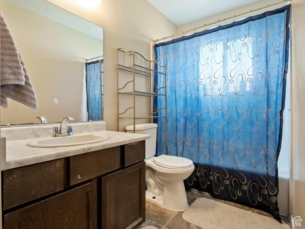 Bathroom with tile floors, vanity with extensive cabinet space, and toilet