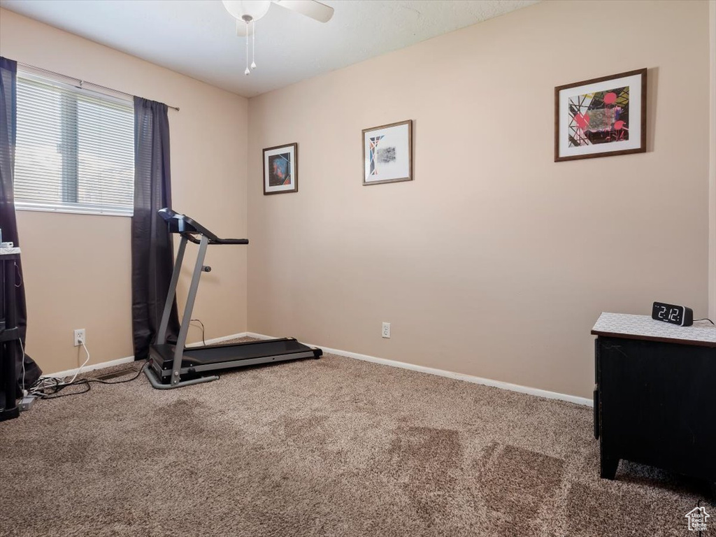Exercise room featuring dark colored carpet and ceiling fan