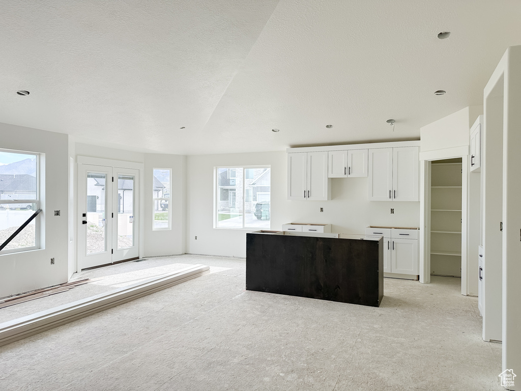 Kitchen with a center island, french doors, light carpet, and white cabinets