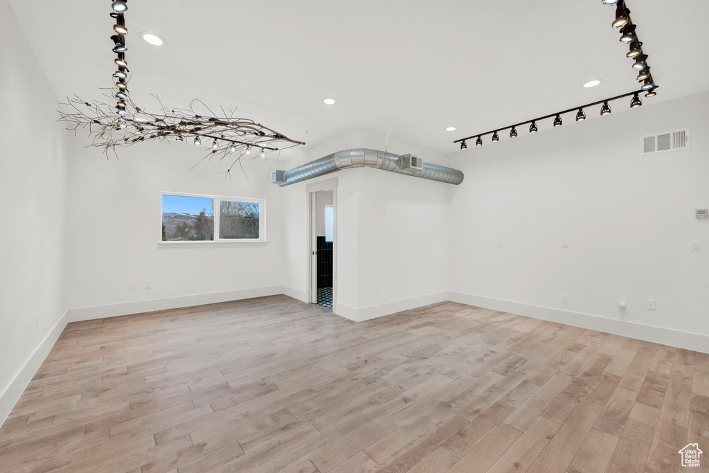 Interior space with rail lighting and light hardwood / wood-style flooring