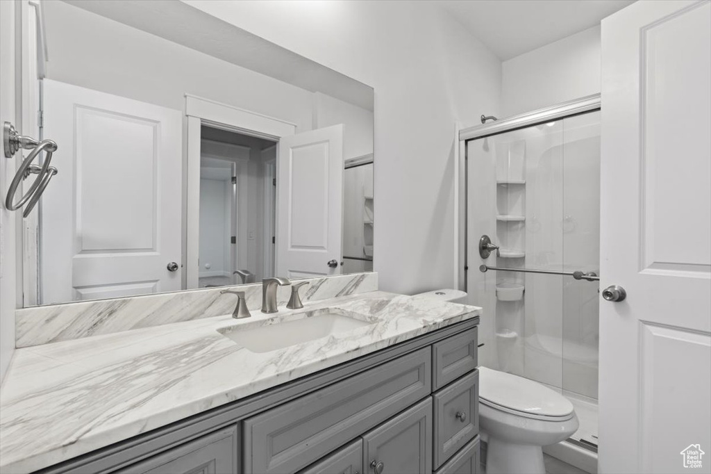 Bathroom featuring walk in shower, toilet, and vanity with extensive cabinet space