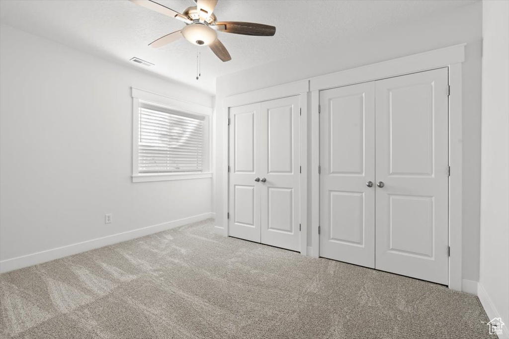 Unfurnished bedroom with ceiling fan and light carpet