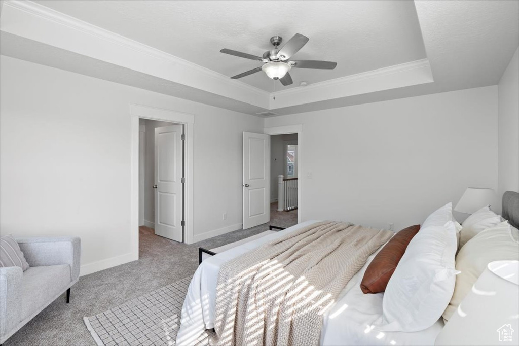 Bedroom featuring light colored carpet, ceiling fan, crown molding, and a raised ceiling