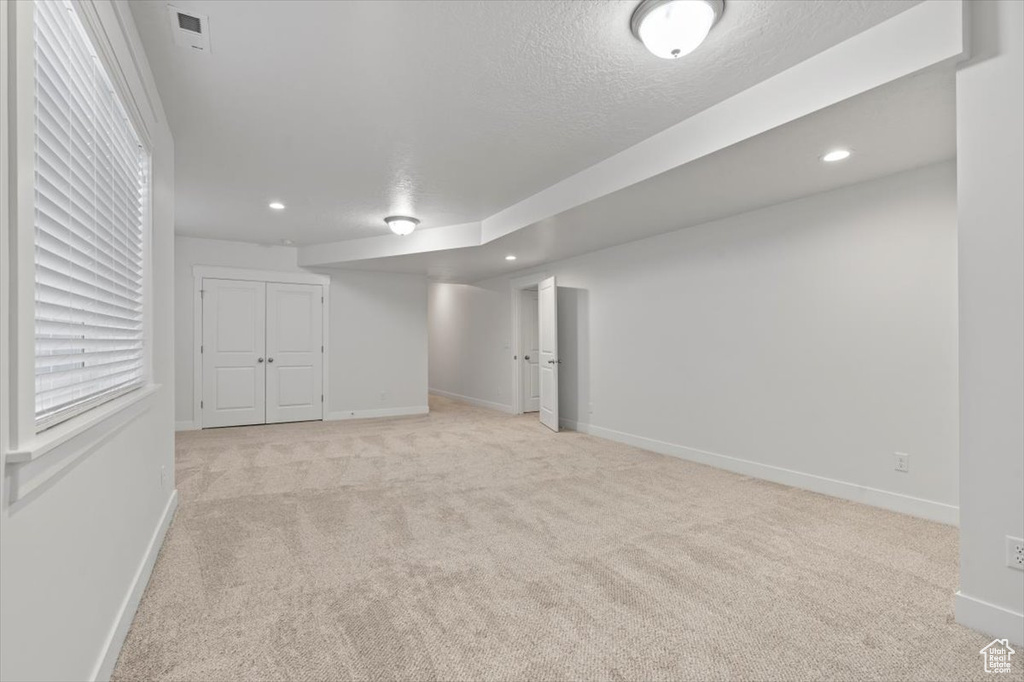 Basement with light carpet and a textured ceiling