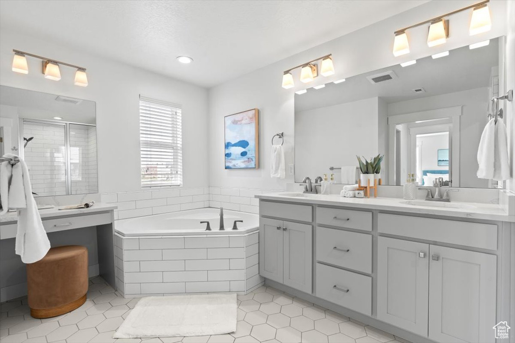 Bathroom with tile flooring, dual sinks, a relaxing tiled bath, and vanity with extensive cabinet space