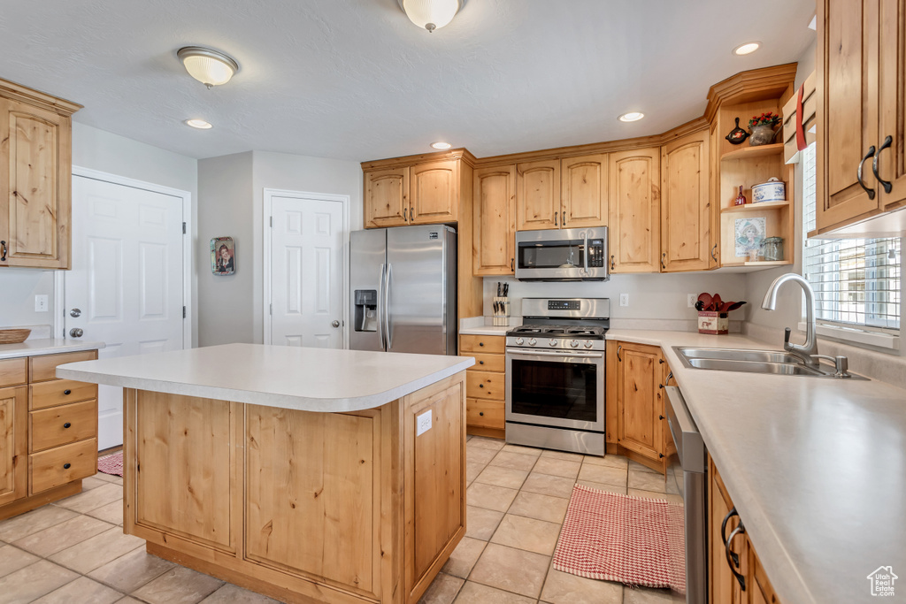 Kitchen with a center island, stainless steel appliances, light tile floors, and sink