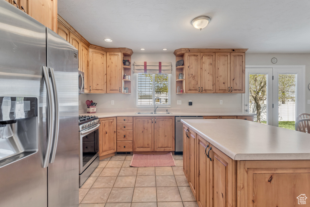 Kitchen featuring sink, light tile floors, and stainless steel appliances