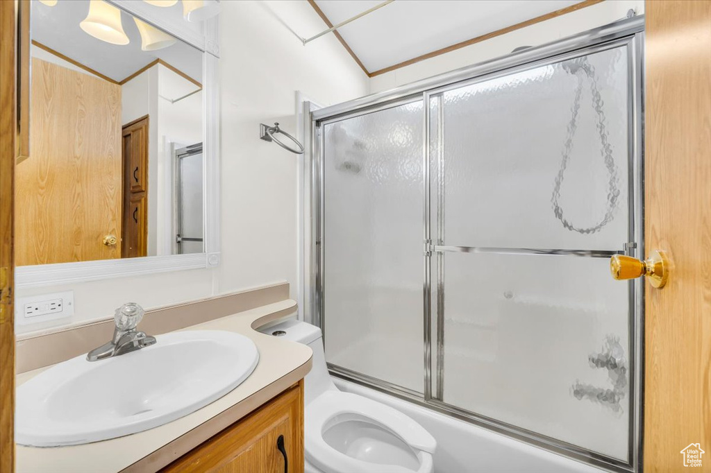 Full bathroom featuring enclosed tub / shower combo, vanity, and toilet