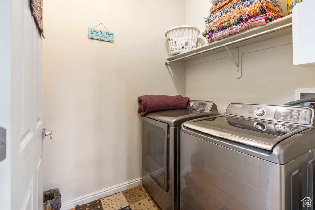 Clothes washing area featuring tile floors and washer and clothes dryer