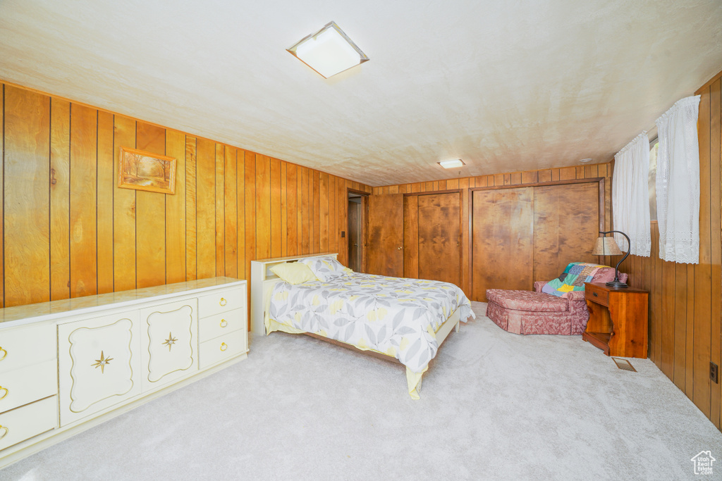 Bedroom with wood walls and light carpet
