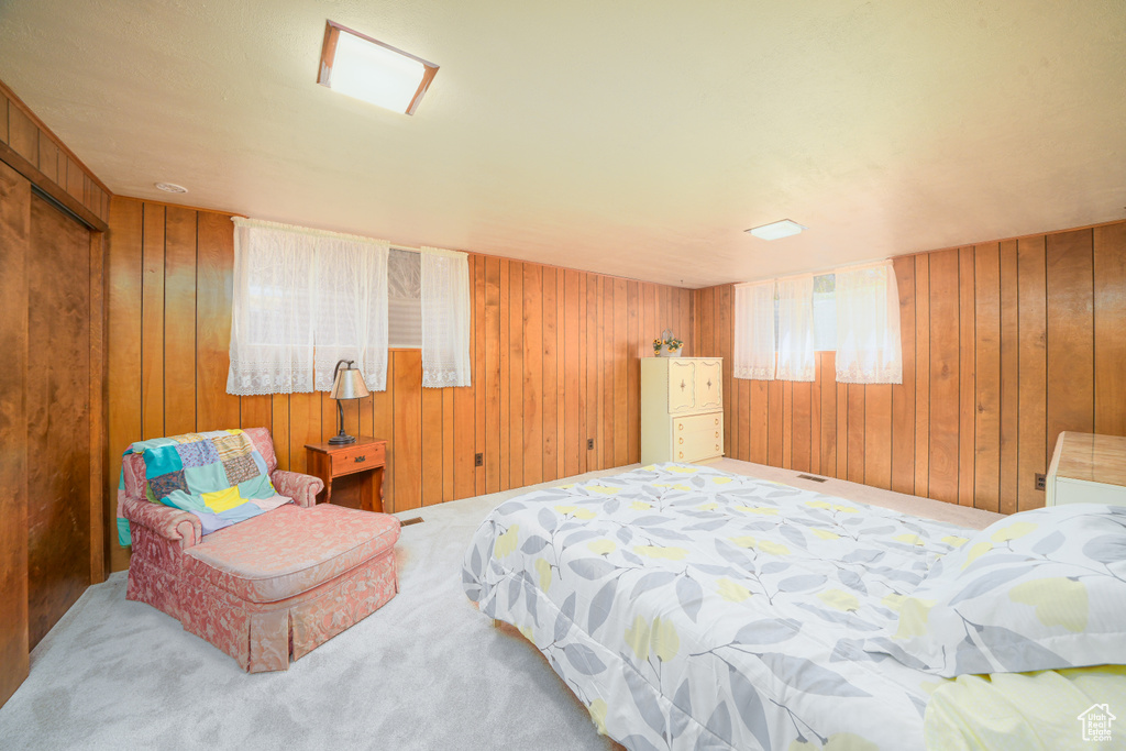 Carpeted bedroom featuring wooden walls