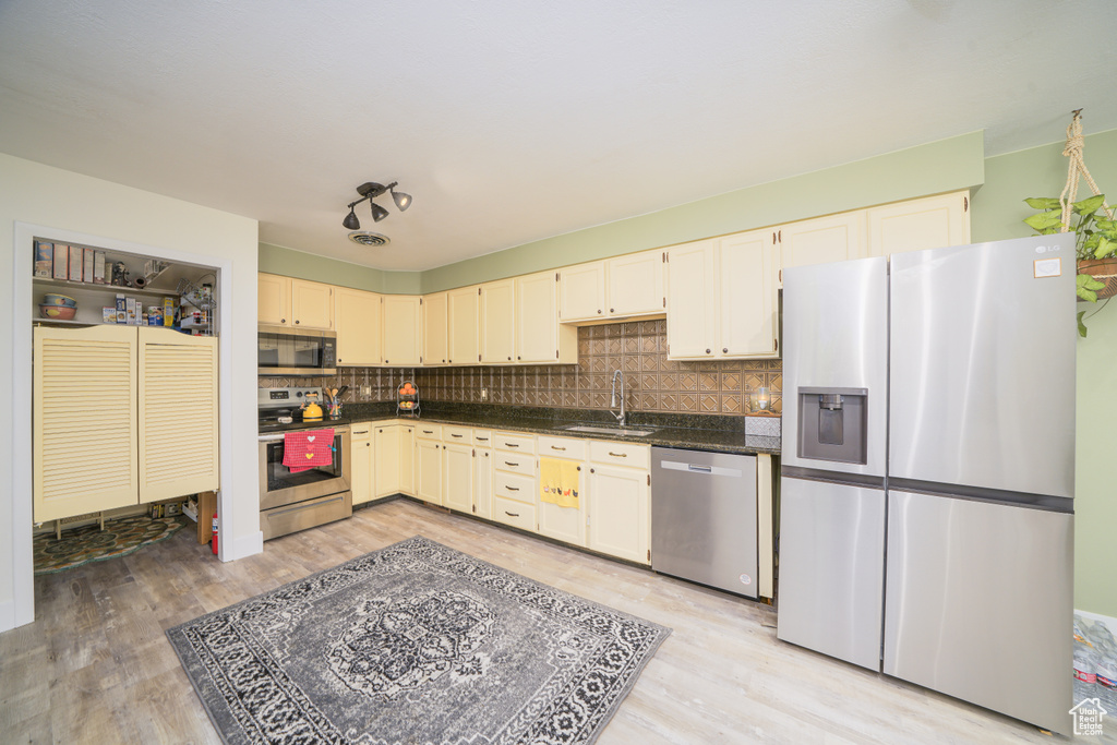Kitchen featuring tasteful backsplash, stainless steel appliances, sink, and light wood-type flooring