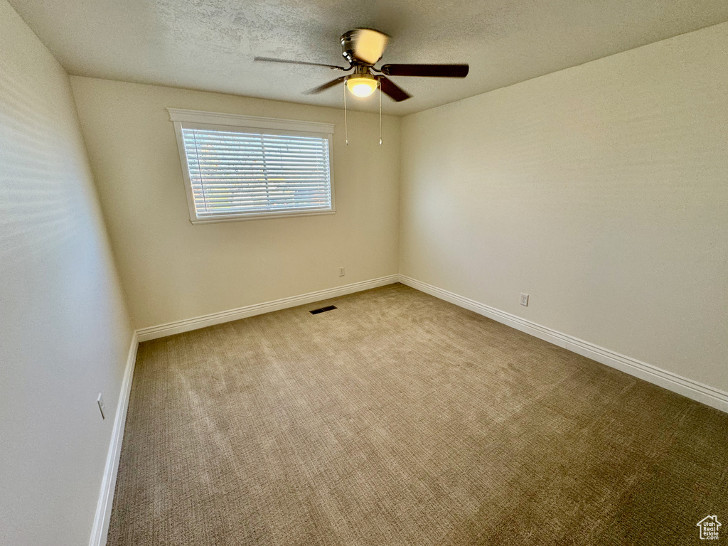 Unfurnished room featuring light colored carpet, a textured ceiling, and ceiling fan