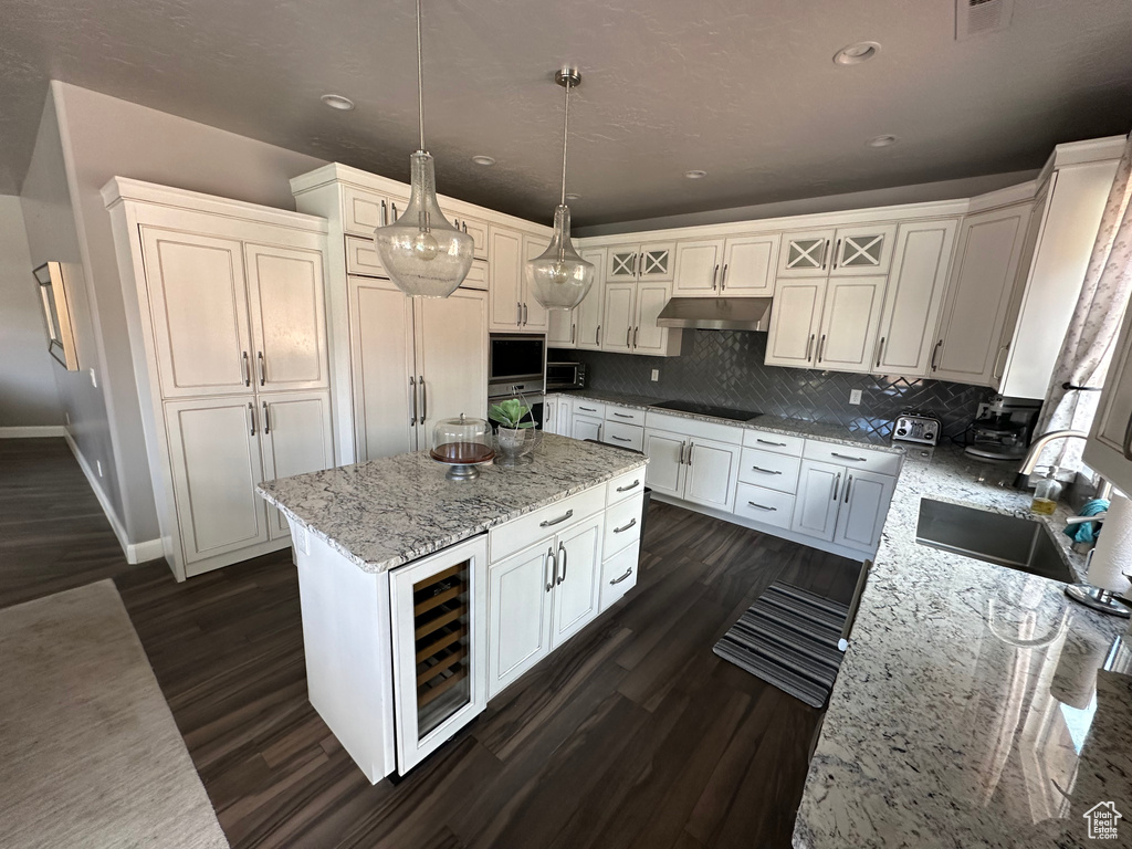 Kitchen featuring decorative light fixtures, beverage cooler, tasteful backsplash, dark hardwood / wood-style flooring, and a center island