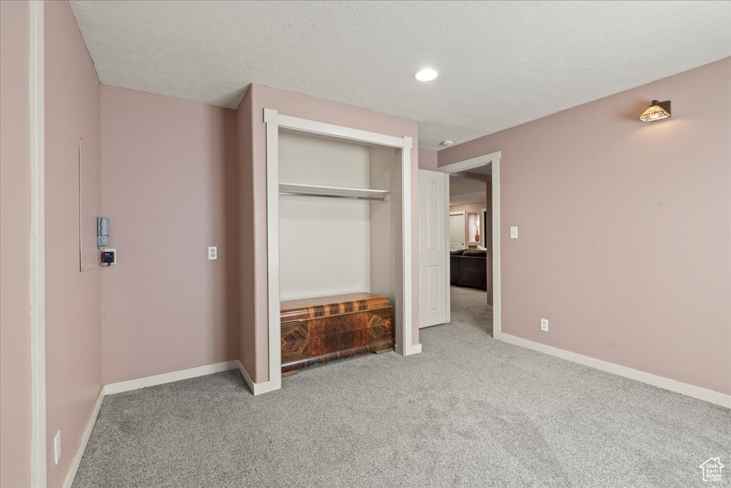 Unfurnished bedroom with a textured ceiling, a closet, and carpet floors