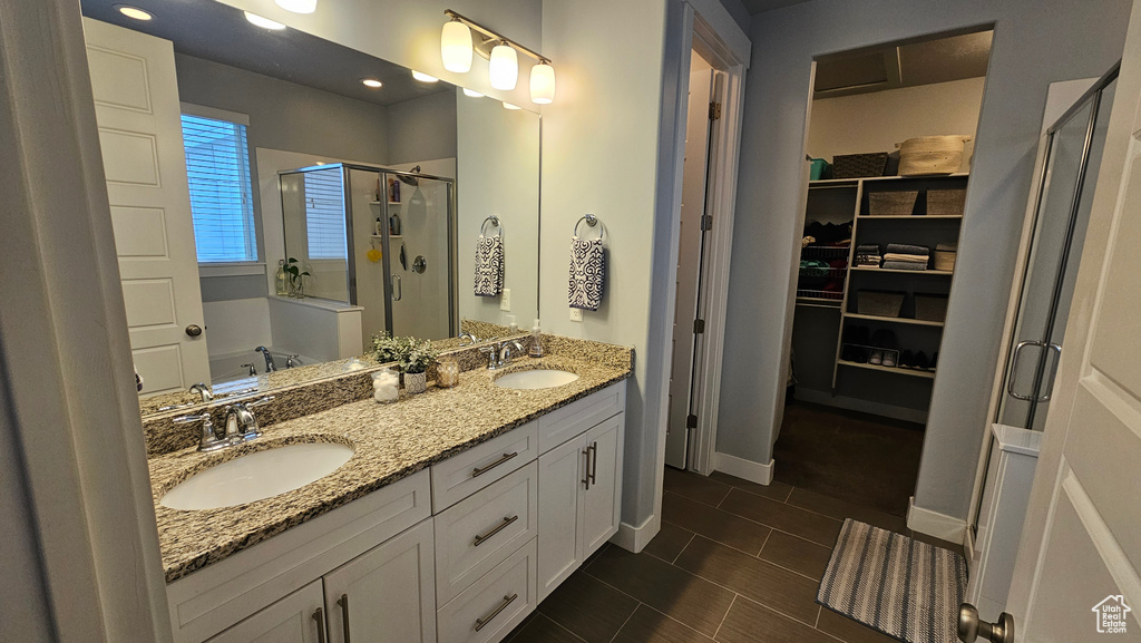 Bathroom featuring dual sinks, tile floors, shower with separate bathtub, and large vanity