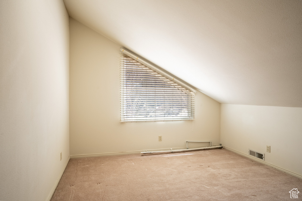 Additional living space featuring light colored carpet and vaulted ceiling