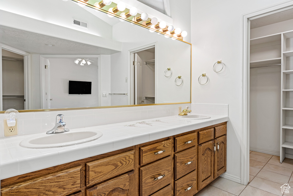 Bathroom with tile flooring, large vanity, and dual sinks
