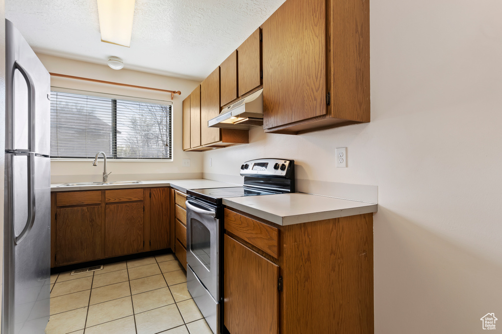 Kitchen with appliances with stainless steel finishes, light tile floors, and sink