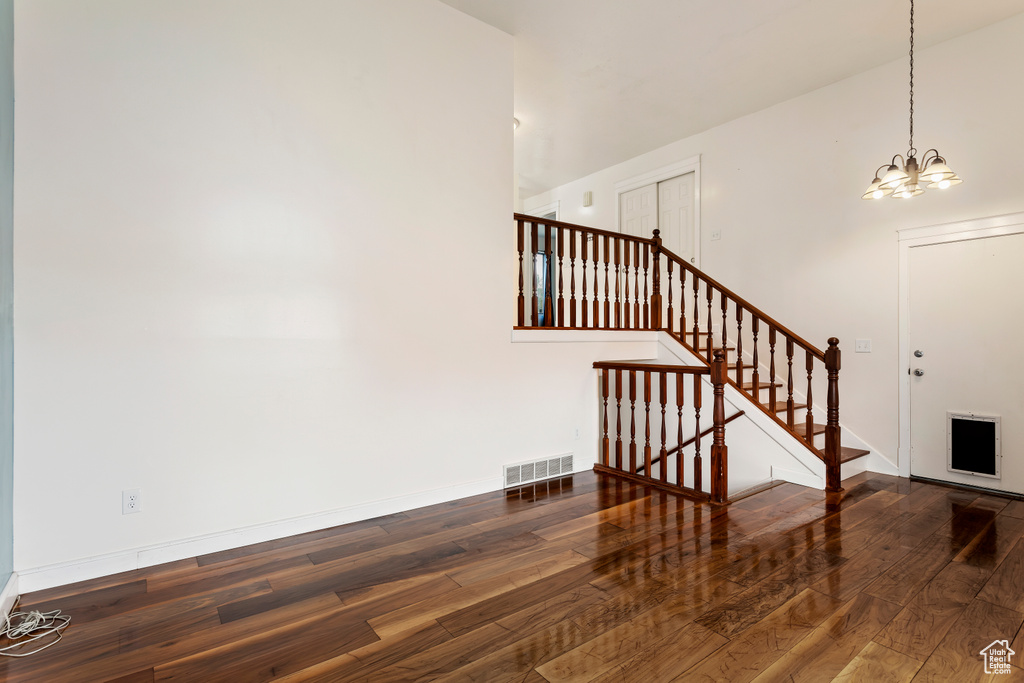 Stairs featuring high vaulted ceiling, dark hardwood / wood-style flooring, and an inviting chandelier