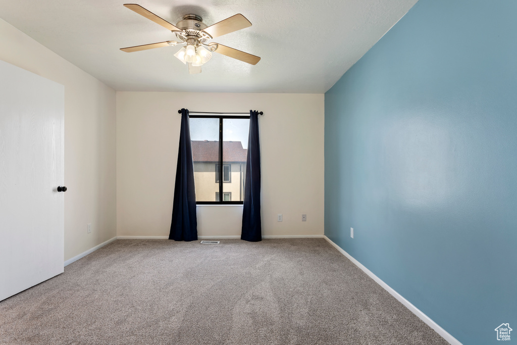 Unfurnished room featuring ceiling fan and light carpet