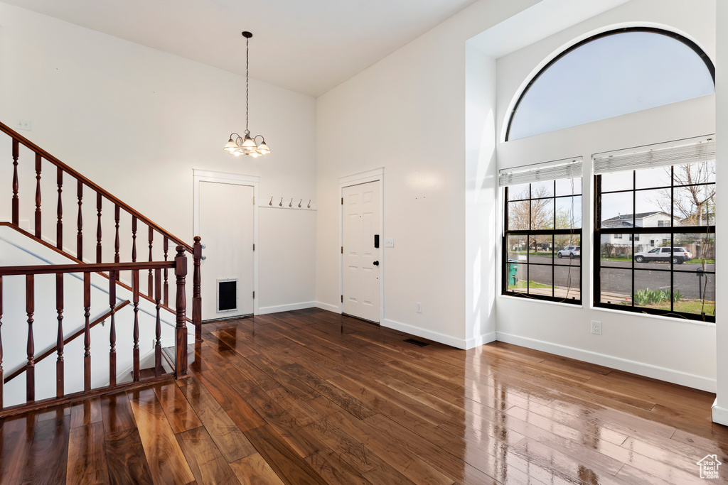 Entryway featuring an inviting chandelier, dark hardwood / wood-style flooring, and a towering ceiling