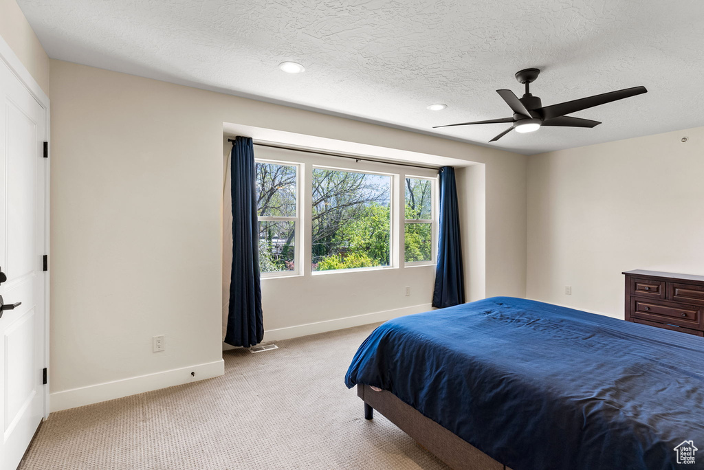 Bedroom featuring a textured ceiling, carpet floors, and ceiling fan