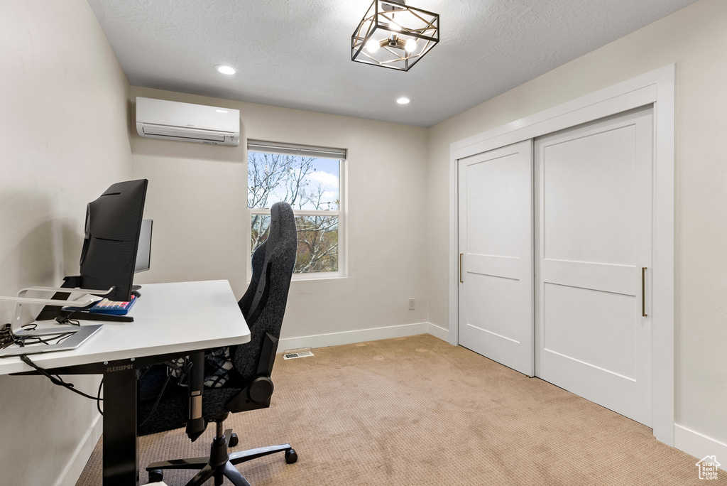 Office space featuring light colored carpet, a wall mounted air conditioner, and a textured ceiling