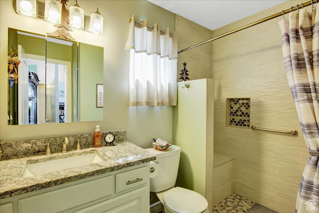 Bathroom with walk in shower, vanity with extensive cabinet space, and toilet