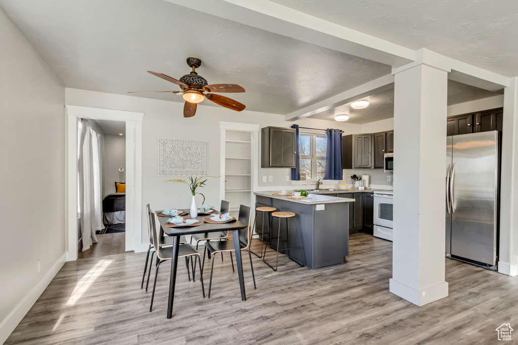 Kitchen with kitchen peninsula, appliances with stainless steel finishes, a breakfast bar area, light hardwood / wood-style floors, and ceiling fan
