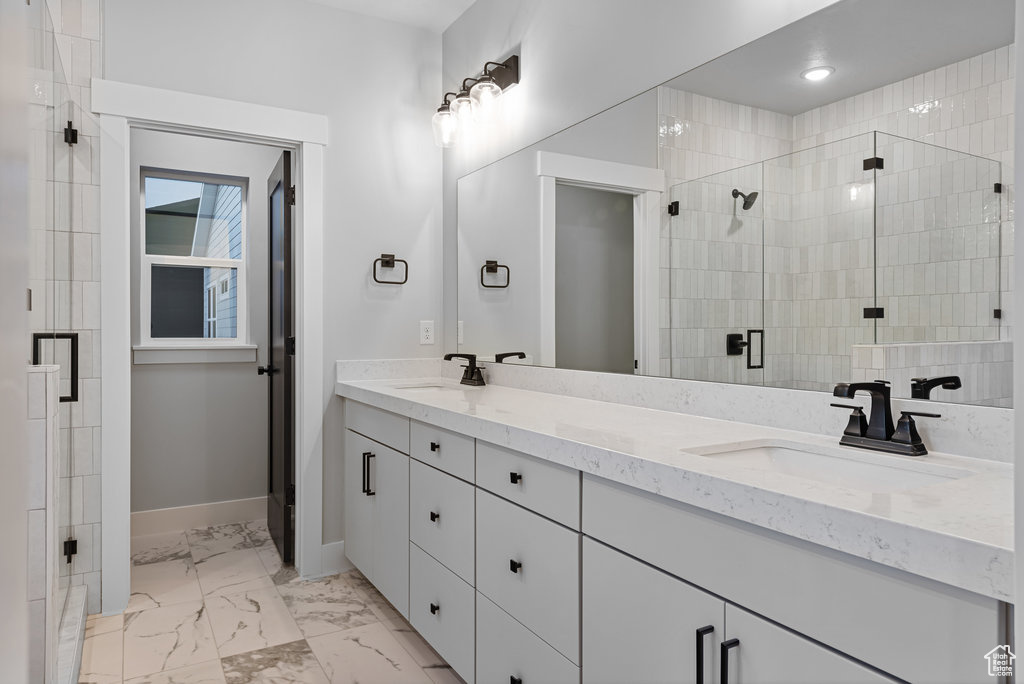 Bathroom featuring a shower with shower door, tile floors, and double sink vanity