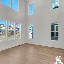 Spare room featuring light hardwood / wood-style floors, a healthy amount of sunlight, and a high ceiling