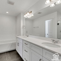 Bathroom with a bathing tub, double vanity, and tile floors