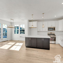 Kitchen with stove, white cabinetry, and a wealth of natural light