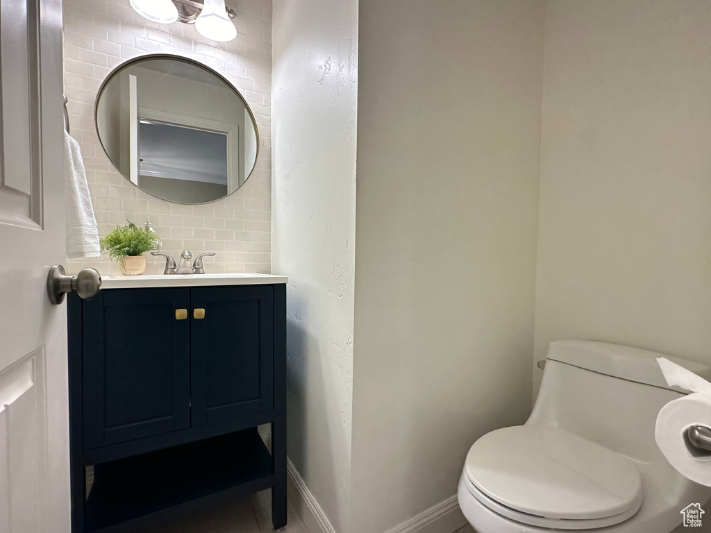 Bathroom featuring backsplash, vanity, tile floors, and toilet