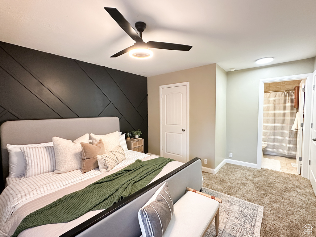 Bedroom featuring ceiling fan, light carpet, and ensuite bathroom