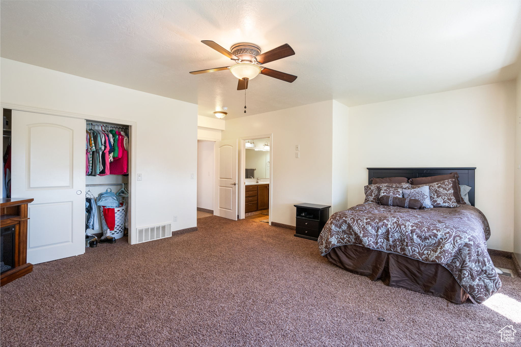Bedroom featuring a closet, ceiling fan, dark carpet, and ensuite bath