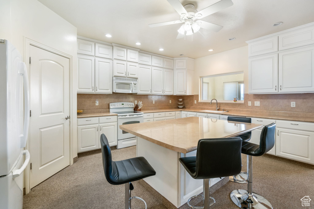 Kitchen with white cabinets, white appliances, and a breakfast bar area