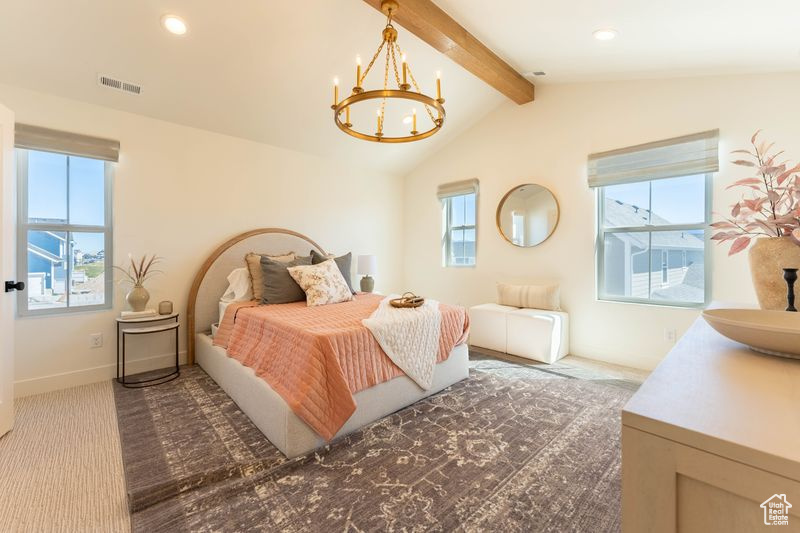 Carpeted bedroom with vaulted ceiling with beams and a chandelier