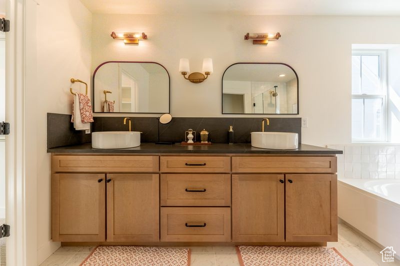Bathroom with tile floors, backsplash, a bathtub, and dual bowl vanity