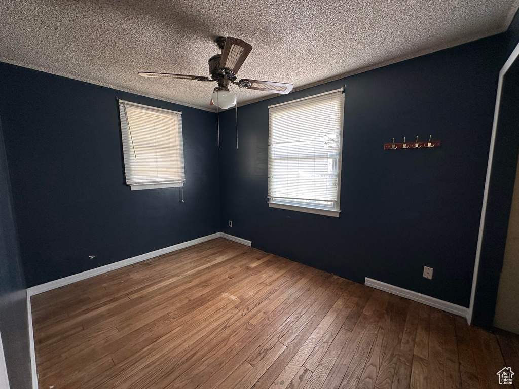 Spare room with dark hardwood / wood-style flooring, ceiling fan, and a textured ceiling