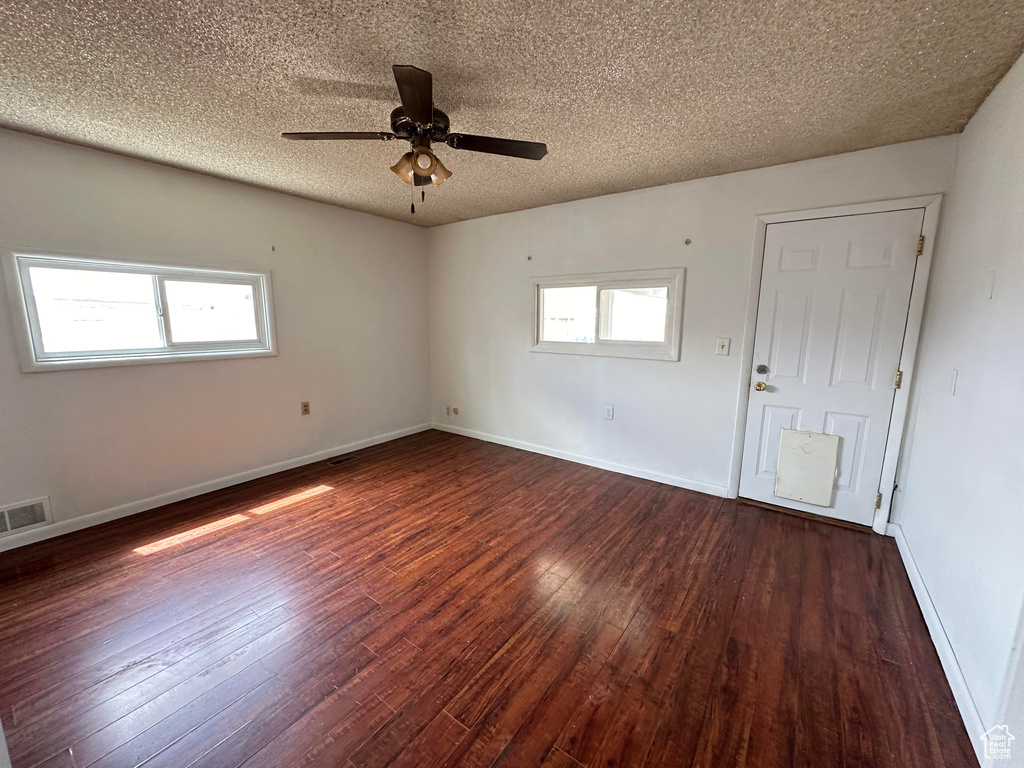 Unfurnished room featuring plenty of natural light, dark hardwood / wood-style flooring, ceiling fan, and a textured ceiling