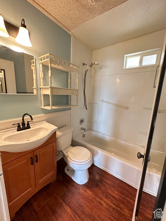 Full bathroom with toilet, wood-type flooring, a textured ceiling, vanity, and washtub / shower combination