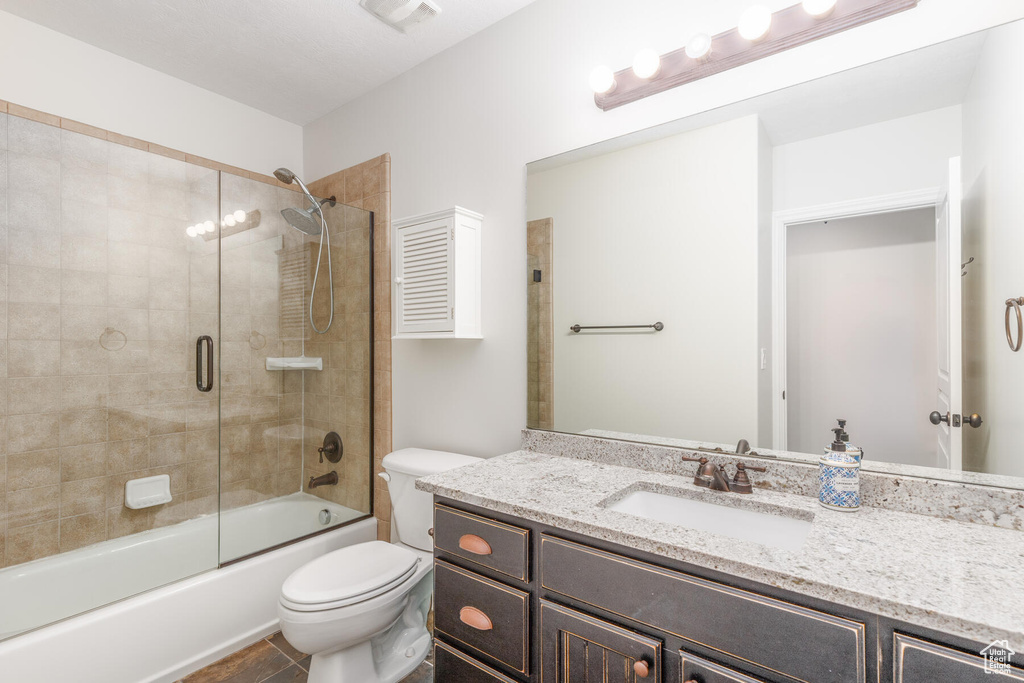 Full bathroom with oversized vanity, tile floors, toilet, and enclosed tub / shower combo